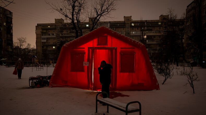 A man smokes outside of an emergency tent where people can warm up following Russia's regular air attacks against the country's energy objects, that leave residents without power, water and heating in the dead of winter, in Kyiv, Ukraine, Tuesday, Jan. 13, 2026. (AP Photo/Danyil Bashakov)