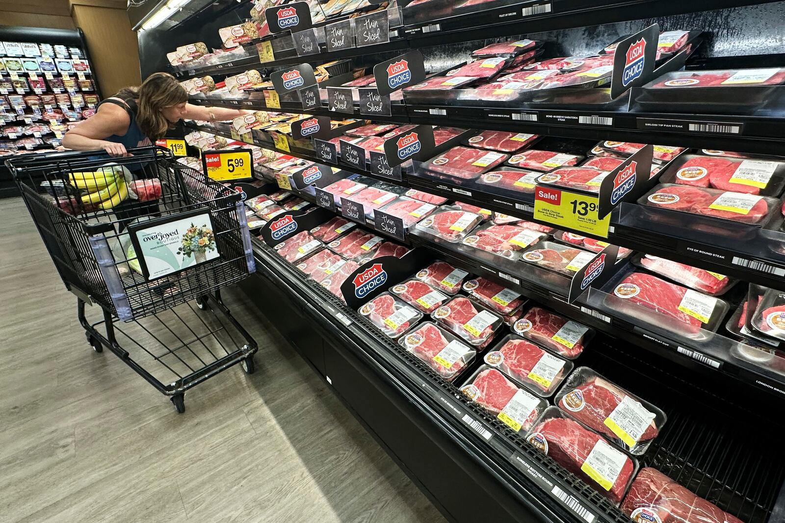 A shopper compares beef prices at a grocery store in Mount Prospect, Ill., Thursday, July 17, 2025. (AP Photo/Nam Y. Huh)