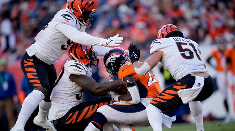 Denver Broncos running back Melvin Gordon (25) is hit by Cincinnati Bengals defensive end Cameron Sample, left, linebacker Germaine Pratt and linebacker Markus Bailey (51) during the first half of an NFL football game, Sunday, Dec. 19, 2021, in Denver. (AP Photo/David Zalubowski)