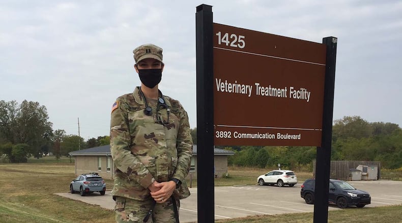 Army Capt. (Dr.) Casey Barwell, the new veterinary branch chief at Wright-Patterson Air Force Base, stands with Suzy, a 12-year-old retired military working dog she and her husband adopted several years ago, in front of the Veterinary Treatment Facility. Skywrighter photo/Amy Rollins