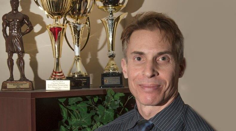 Eric Thayer, 88th Force Support Squadron Airman & Family Readiness flight chief, stands next to some of his many fitness awards inside his office at Wright-Patterson Air Force Base, Ohio, Jan. 10. Thayer has competed in several fitness competitions, such as for the Global Bodybuilding Organization and Cincinnati Natural Bodybuilding Championships. (U.S. Air Force photo/Michelle Gigante)