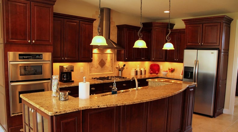 Set in a rectangular space with 2 walls of windows the breakfast area connects to the open kitchen, where granite counters and oversized cabinets frame the work space. Contemporary hanging lights accent the center island.