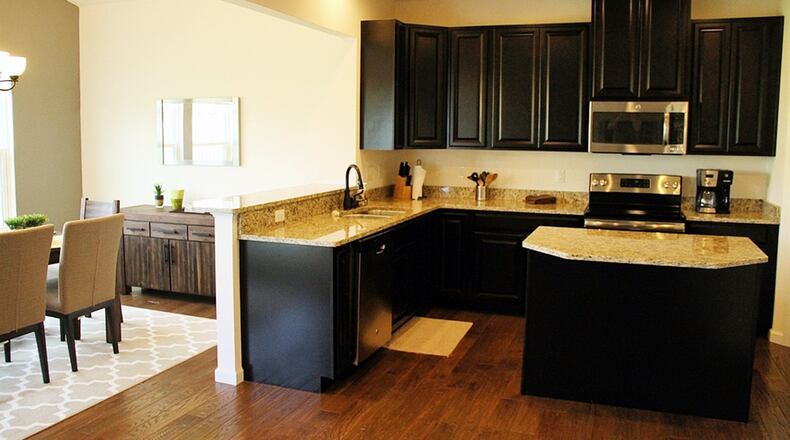 In the open kitchen, 42-inch, espresso-stained wood cabinets and granite counters surround the L-shaped work space, which is augmented by a matching center island with an overhang for bar seating.