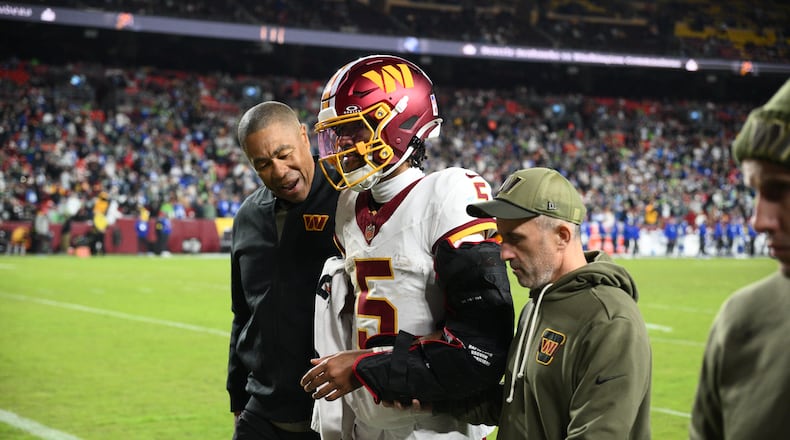 Washington Commanders quarterback Jayden Daniels (5) is helped off the field after he injuring his arm during a play in the second half of an NFL football game, Sunday, Nov. 2, 2025, in Landover, Md. (AP Photo/Nick Wass)