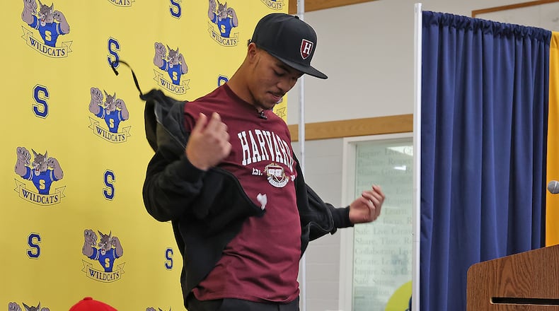 Springfield High School football standout Delian Bradley takes off his jacket to reveal his college selection Wednesday during National Signing Day. Delian chose Harvard from the 31 college scholarship offers. BILL LACKEY/STAFF
