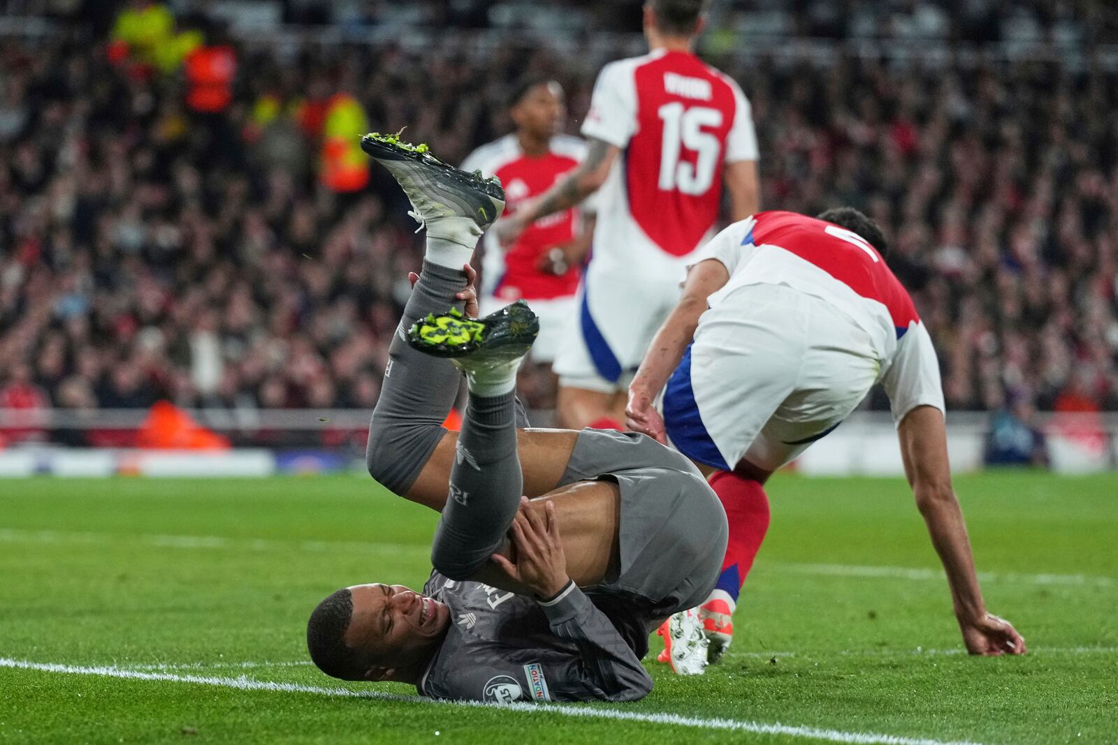 Real Madrid's Kylian Mbappe, bottom, goes to ground after a challenge with Arsenal's William Saliba during the Champions League quarterfinal first leg soccer match between Arsenal and Real Madrid at the Emirates Stadium in London, Tuesday, April 8, 2025. (AP Photo/Frank Augstein)