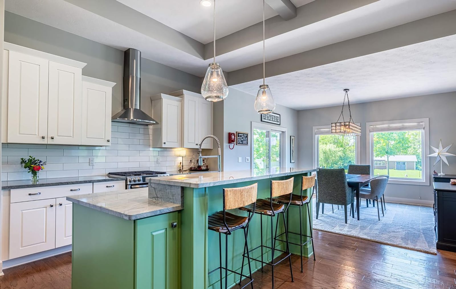 The kitchen has hardwood flooring, pendant lights over the island and high end appliances including a gas range with double ovens.