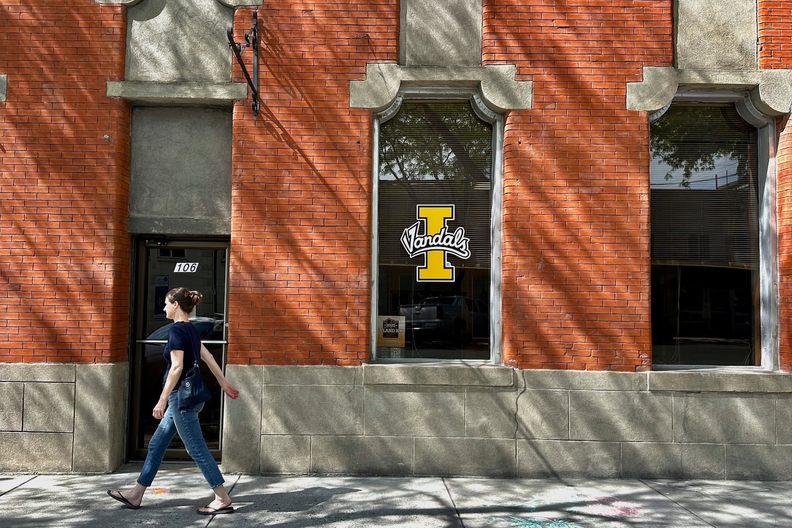 A person walks on a downtown street in Moscow, Idaho, in front of a building with a University of Idaho logo on a window on Tuesday, July 1, 2025. (AP Photos/Manuel Valdes)