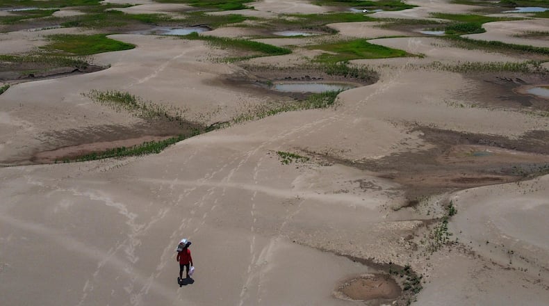 FILE - A resident of a riverside community carries food and containers of drinking water after being distributed due to the ongoing drought in Careiro da Varzea, Amazonas state, Brazil, Oct. 24, 2023. (AP Photo /Edmar Barros, File)