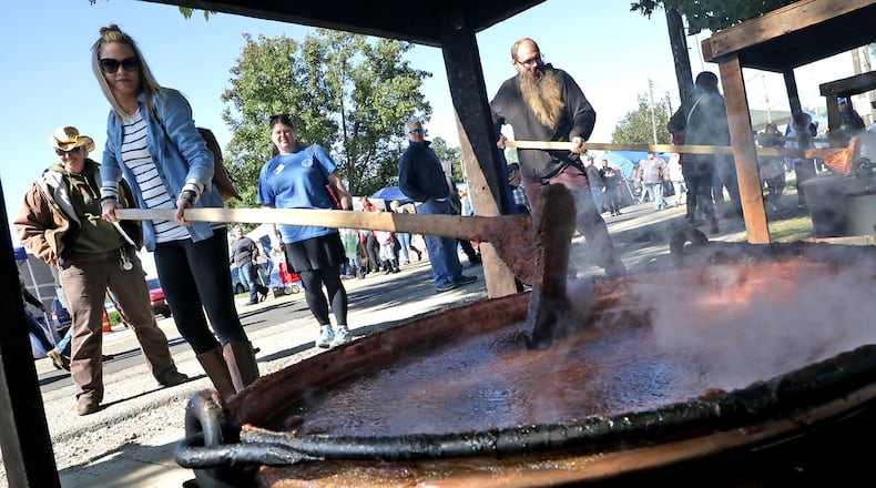 Shannon Webb takes a turn at stirring one of the giant kettles of apple butter cooking over an open fire at the 2019 Enon Apple Butter Festival Saturday. Organizers have canceled this year’s festival due to the coronavirus pandemic. BILL LACKEY/STAFF
