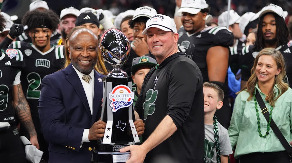 CEO of Scooter's Coffee Joe Thornton, left, presents the winner's trophy to Ohio interim head coach John Hauser after the Frisco Bowl NCAA college football game against UNLV Tuesday, Dec. 23, 2025, in Frisco, Texas. (AP Photo/LM Otero)