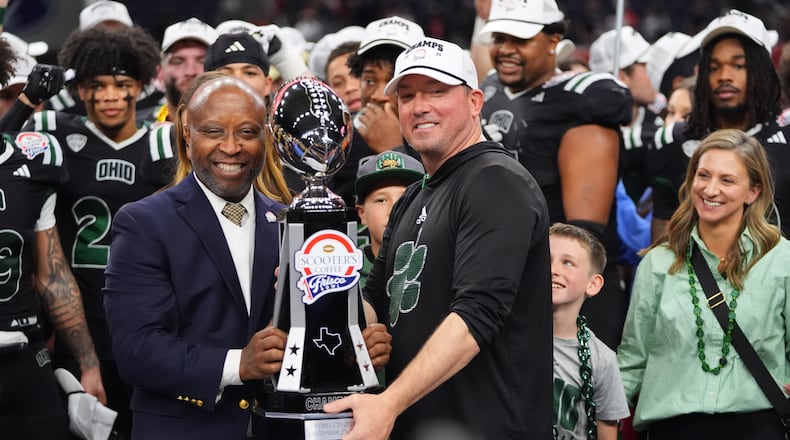 CEO of Scooter's Coffee Joe Thornton, left, presents the winner's trophy to Ohio interim head coach John Hauser after the Frisco Bowl NCAA college football game against UNLV Tuesday, Dec. 23, 2025, in Frisco, Texas. (AP Photo/LM Otero)