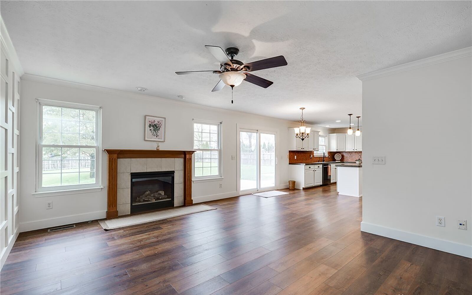 The family room has a gas fireplace, hardwood flooring and a ceiling fan.