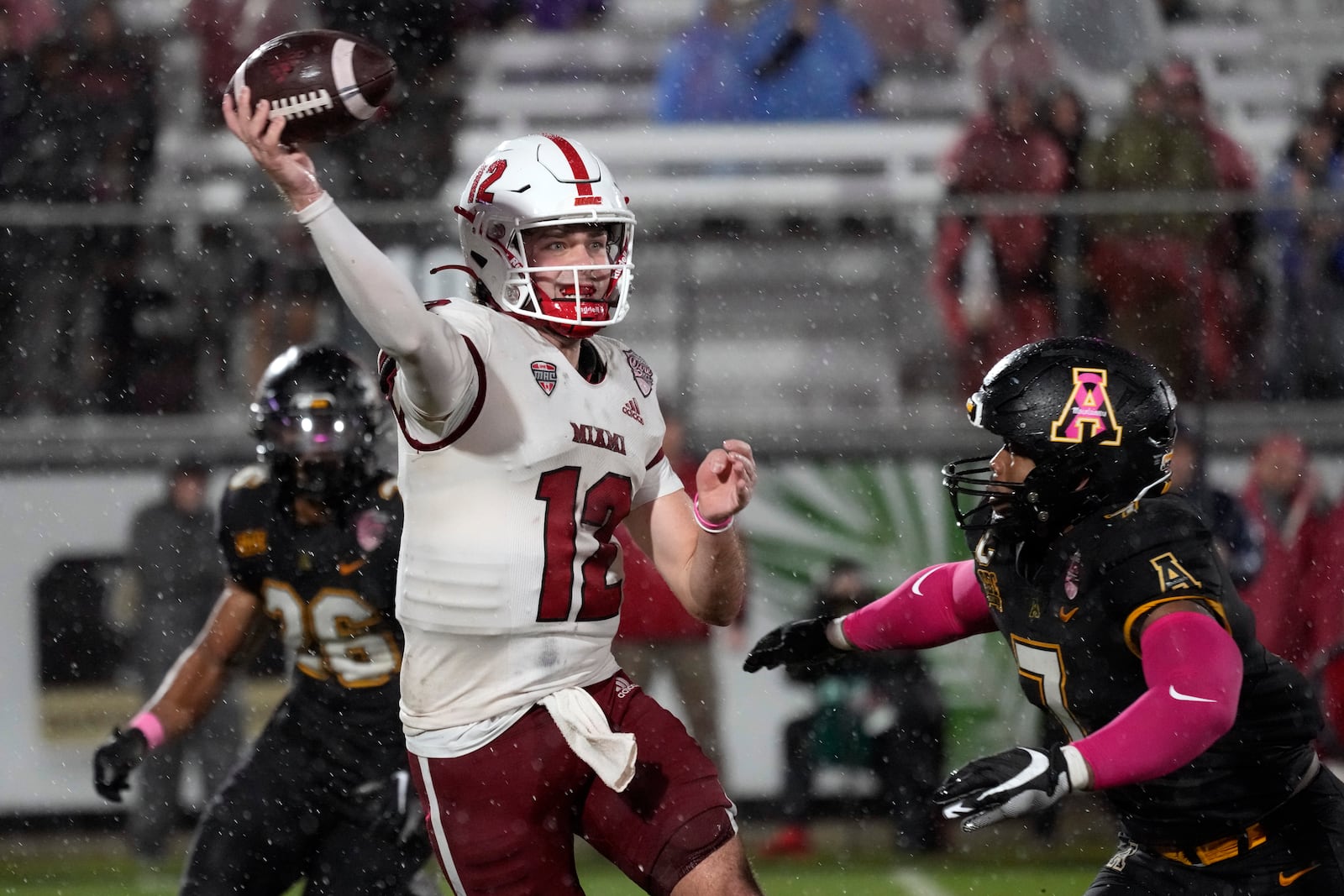 Miami (Ohio) quarterback Henry Hesson (12) throws a pass as he is pressured by Appalachian State linebacker Andrew Parker Jr., right, and linebacker Caden Sullivan (26) during the second half of the Cure Bowl NCAA college football game, Saturday, Dec. 16, 2023, in Orlando, Fla. (AP Photo/John Raoux)