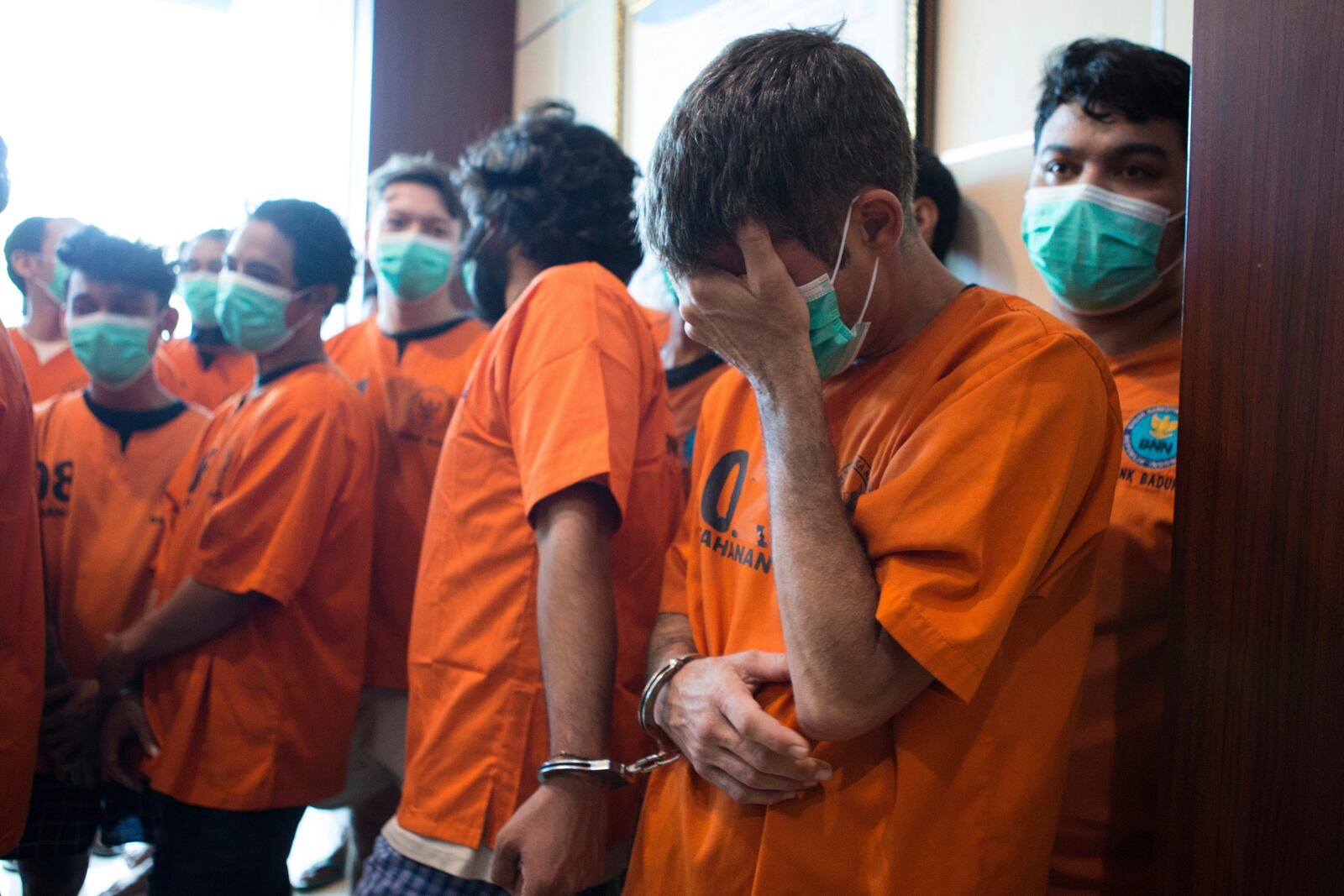 Australian national identified only as P.R., front right, who is handcuffed together with an Indian national identified as H.V., reacts as they are presented to the media with other drug suspects following their arrests, during a National Narcotics Agency press conference in Denpasar, Bali, Indonesia Thursday, June 5, 2025. (AP Photo/Firdia Lisnawati)