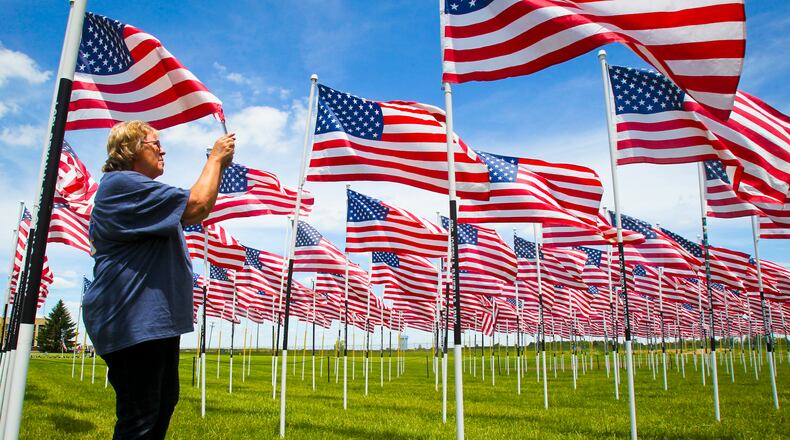 Debbie Monroe, American Legion Auxiliary 4th District President, takes a photograph of a family members name and flag in the Flags of Honor display. a tribute to Ohio fallen service members in the war on terrorism, on display as part of âBring Back the Meaning of Memorial Dayâ held at the National Voice of America Museum of Broadcasting in West Chester, Saturday, May 24, 2014. The event, sponsored by local American Gold Star Mothers, runs May 24-26 from 10am-6pm. GREG LYNCH / STAFF