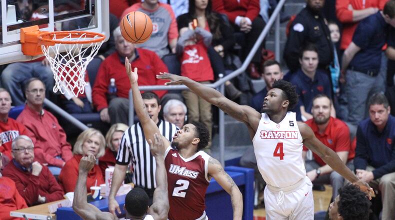 Massachusetts’ Luwane Pipkins shoots between Dayton’s Trey Landers, left, and Jordan Davis, right, on Saturday, Jan. 6, 2018, at UD Arena. David Jablonski/Staff
