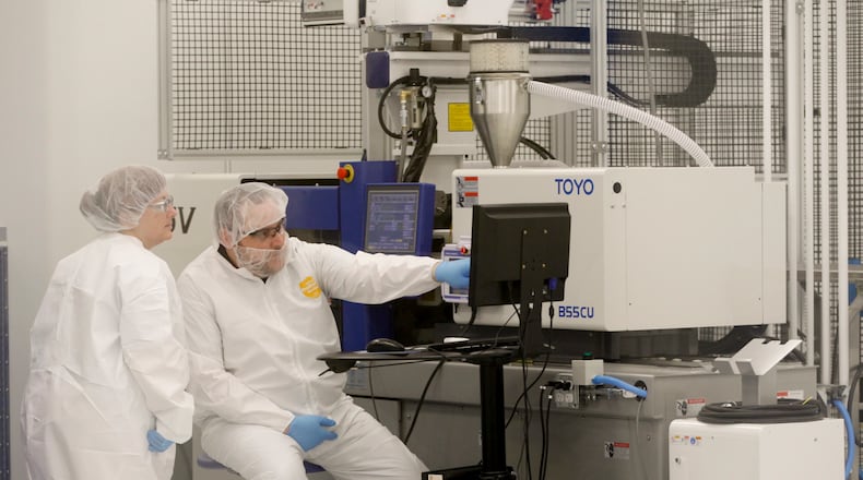 DG Medical in Centerville is a plastics molder of medical devices. Wendy Brewer (left) and Brad Burns (right) work at an all electric injection molding press in the clean room at the site. LISA POWELL / STAFF