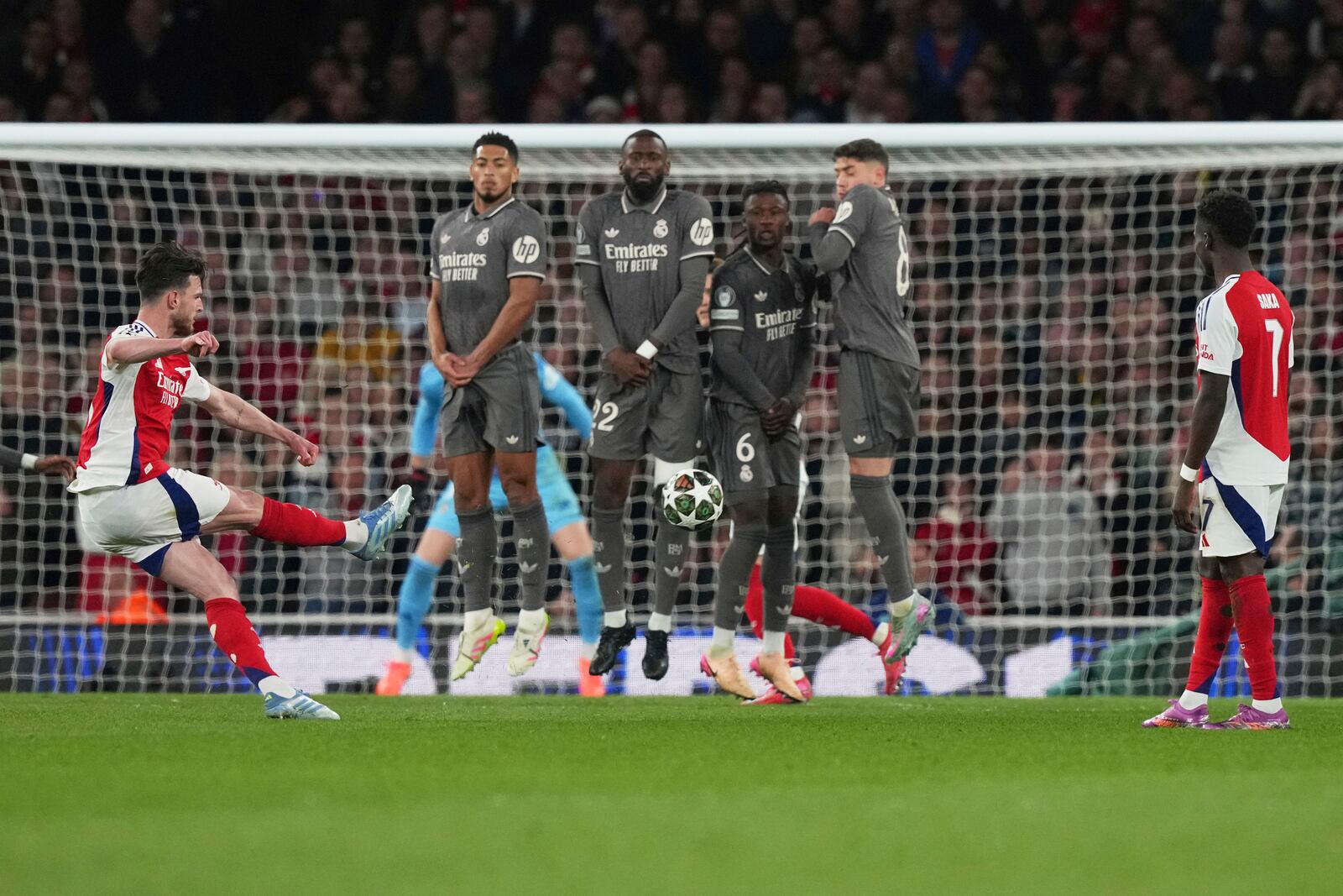 Arsenal's Declan Rice, left, scores his side's opening goal during the Champions League quarterfinal first leg soccer match between Arsenal and Real Madrid at the Emirates Stadium in London, Tuesday, April 8, 2025. (AP Photo/Frank Augstein)