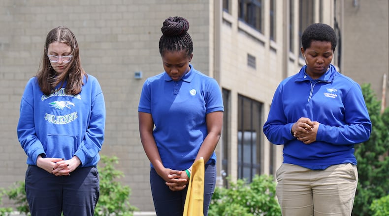 Chaminade-Julienne students pray outside the high school on Thursday. About 20 students and staff participated in a prayer circle that focused on peace ahead of the NATO summit that will take place in downtown Dayton later this month. Flags from NATO countries were placed in a circle in a lawn between the school and athletic fields. BRYANT BILLING / STAFF