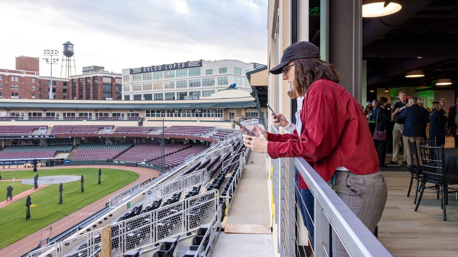 Jenn Gayda, a promotions director for iHeartRadio, looks at her phone along a railing in the new Diamond Club at Day Air Ballpark on Wednesday, Nov. 5. The new 5,000-square-foot venue is located on the side of the stadium nearest Monument Avenue and is on the left-field line. BRYANT BILLING/STAFF