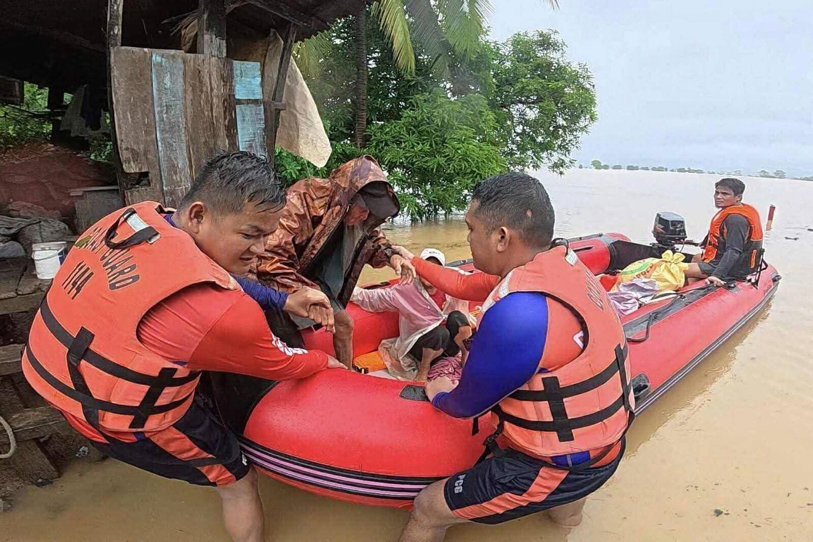 In this photo provided by the Philippine Coast Guard, rescuers assist a man to a rubber boat as they bring him to safer grounds following floods in Mamburao, Occidental Mindoro province, Philippines on Wednesday July 23, 2025. (Philippine Coast Guard via AP)3