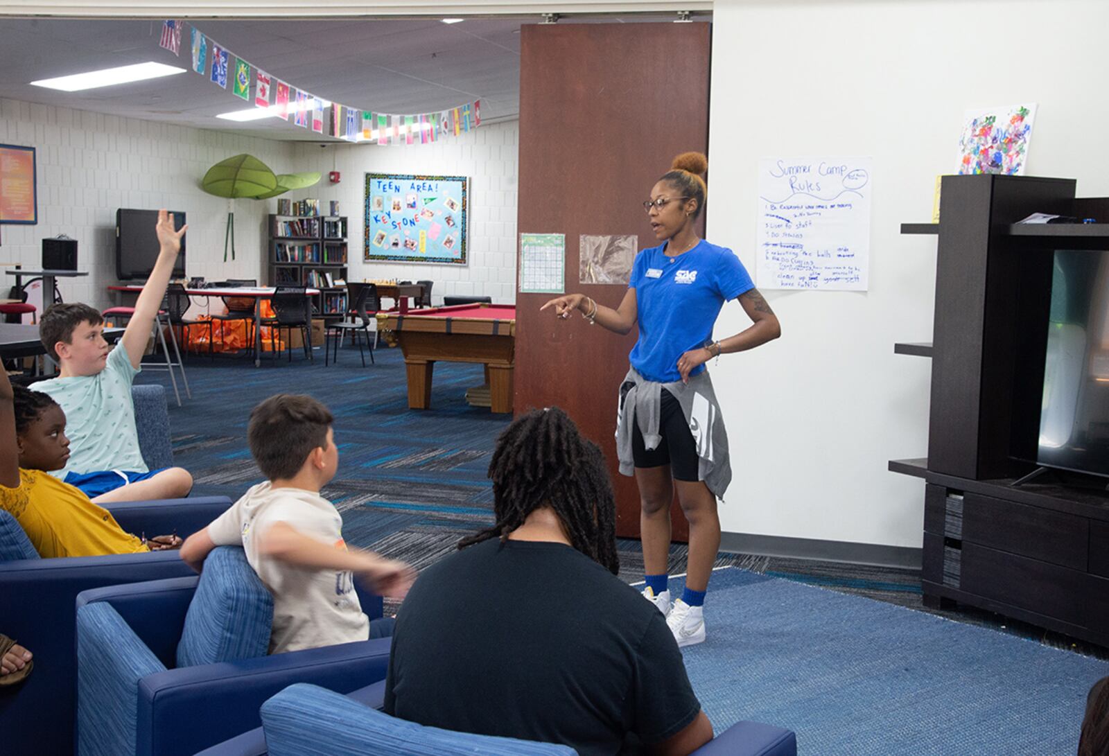 De’Shae Scott, youth programs assistant (middle), discusses what games and entertainment is available at the Prairies Youth Center on June 22. U.S. AIR FORCE PHOTO/AIRMAN 1ST CLASS JAMES JOHNSON