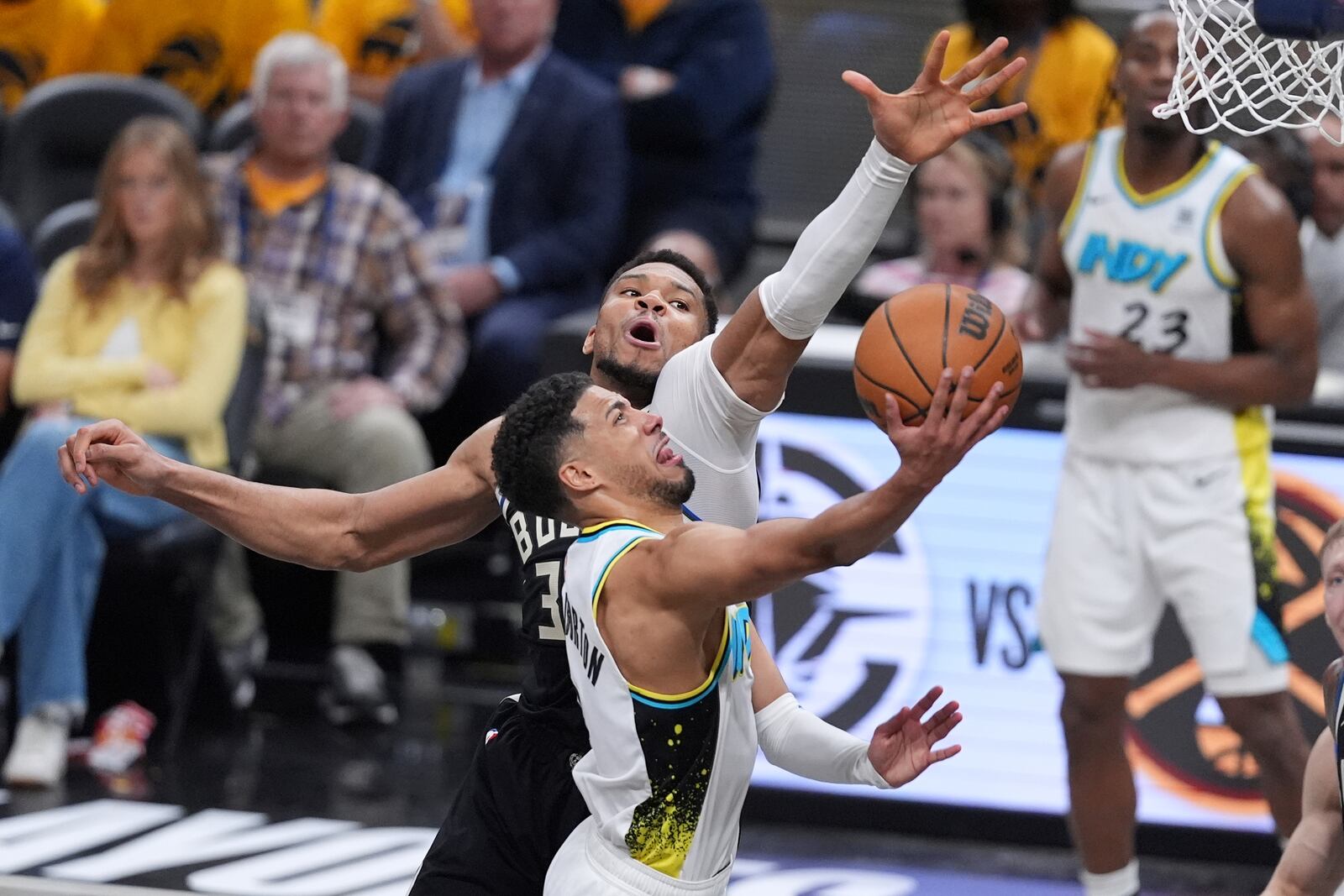 Indiana Pacers' Tyrese Haliburton, front, heads to the basket as Milwaukee Bucks' Giannis Antetokounmpo defends during the second half of a first-round NBA basketball playoff game, Saturday, April 19, 2025, in Indianapolis. (AP Photo/Michael Conroy)