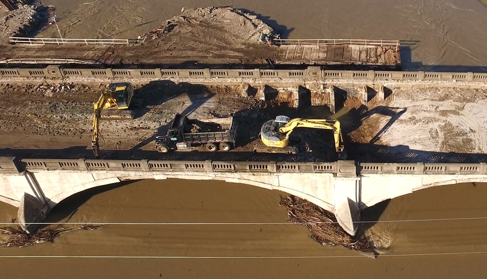 Contractors have started the demolition process for the old Keowee Street Bridge over the Great Miami River.  Decking has bee removed about halfway across the span.  Dirt and foundry slag that filled the concrete based bridge is being removed before the concrete structure is demolished. The bridge replacement will take about two years according to Montgomery County Engineer Paul Gruner.   TY GREENLEES / STAFF