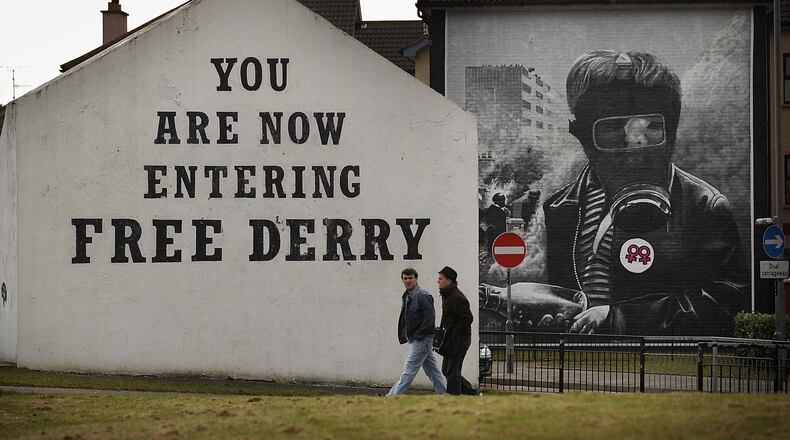 DERRY, NORTHERN IRELAND - MARCH 15:  Two residents walk past Free Derry Corner in the Catholic Bogside area of Derry on March 15, 2010 in Northern Ireland. The Bloody Sunday Inquiry chaired by Lord Saville was established in 1998 to look at the shooting dead of 14 civil rights marchers by the British Army in Derry, Northern Ireland on January 30, 1972. Lord Saville and his fellow judges have spoken to 921 witnesses during the longest legal proceedings in British and Irish history. The report is due to be sent to the Government by the end of March 2010.  (Photo by Peter Macdiarmid/Getty Images)