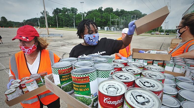 Voluteers prepare for a free food give away at the Nutter Center. MARSHALL GORBY \ STAFF