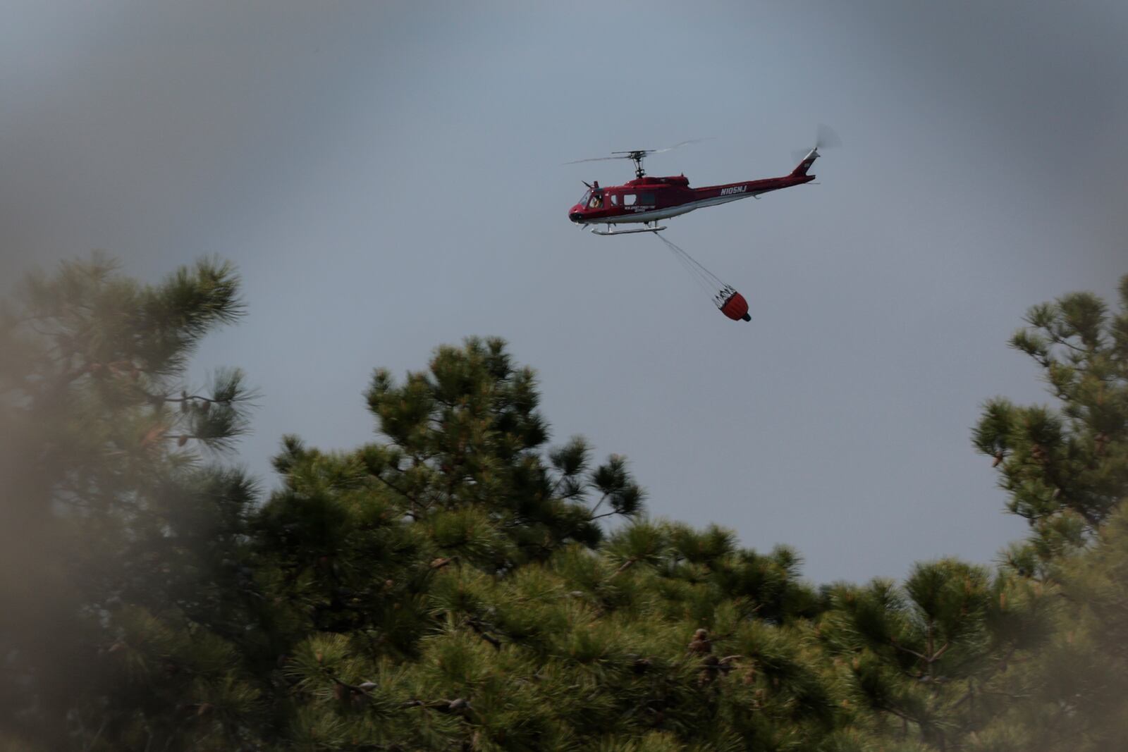 A helicopter helps fight the wildfire close to the Garden State Parkway's Waretown toll plaza in New Jersey on Wednesday, April 23, 2025. (Elizabeth Robertson /The Philadelphia Inquirer via AP)