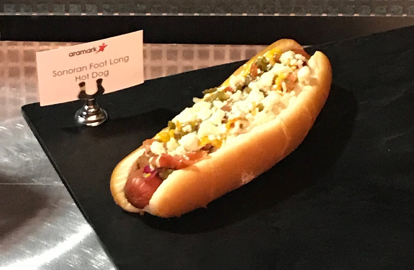 The Sonoran Foot Long Dog available at Paul Brown Stadium is topped with bacon crumbles as well, but also pinto beans, mustard, mayo, salsa verde, queso fresco, and diced onions, tomatoes and jalapenos. AARON EPPLE/CONTRIBUTED