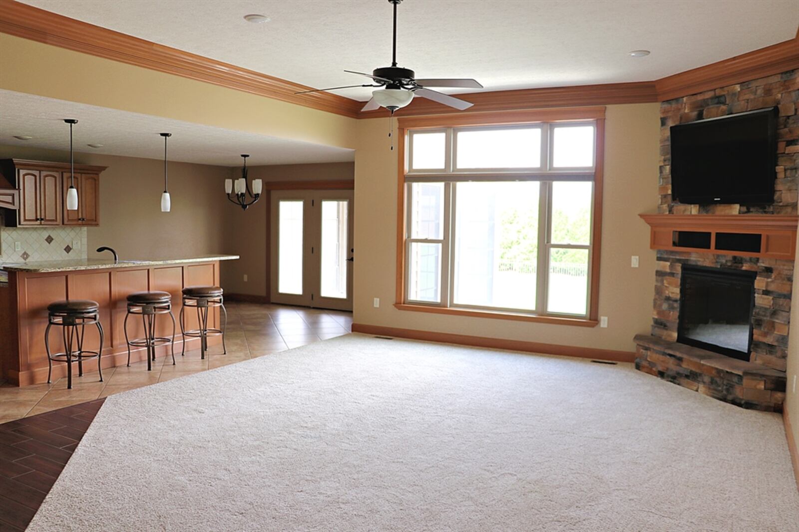 Separated by flooring treatment, the great room has a wall of windows and a gas fireplace tucked into one corner. 