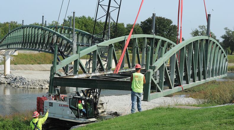 Workers are dismantling the Deeds Point Park Pedestrian Bridge Thursday that spans the Mad River. The 440-foot bridge, part of the roughly $30 million RiverScape project, was closed in November 2018 because of safety and stability concerns. The center section will be dismantled next week.