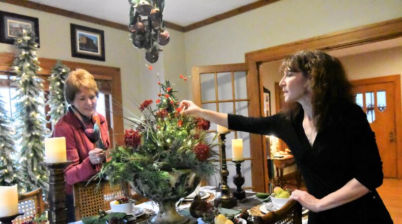 Diana Begley and Sonya Lyons work with pieces selected for decorating the dining room table of Lyons home for the annual Christmas in the Village Home Tour. CONTRIBUTED