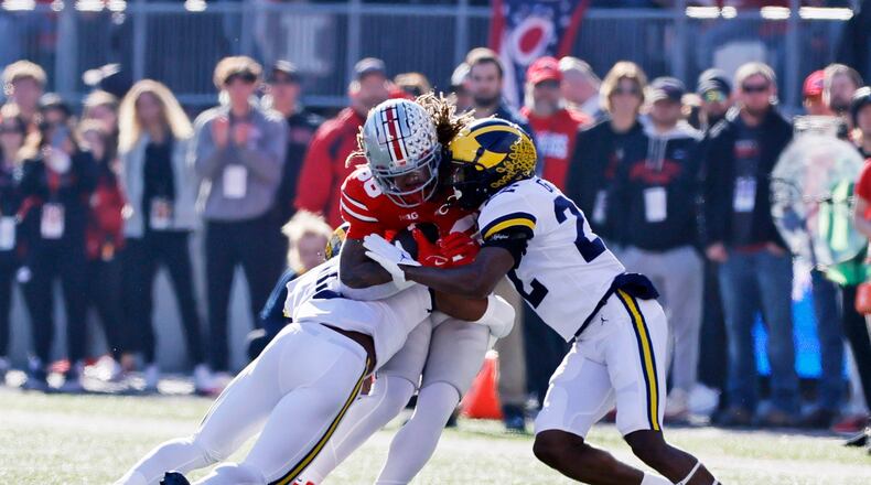 Michigan defensive back R.J. Moten, left, and defensive back Gemon Green tackle Ohio State tight end Gee Scott during the first half of an NCAA college football game on Saturday, Nov. 26, 2022, in Columbus, Ohio. (AP Photo/Jay LaPrete)