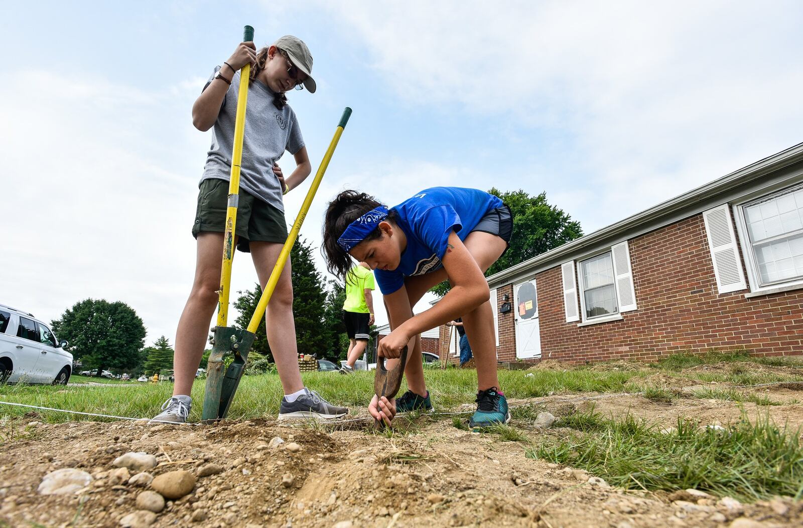 Madelyn Stewart, 15, from North Carolina, and Maddison Surles, 15, from Oklahoma, dig post holes Tuesday, June 26, for a wheelchair ramp they are building at a home on Hammond Boulevard. More than 400 young adults and adult leaders from 10 states are in Butler County this week to conduct home repairs for 53 homeowners throughout the county. 