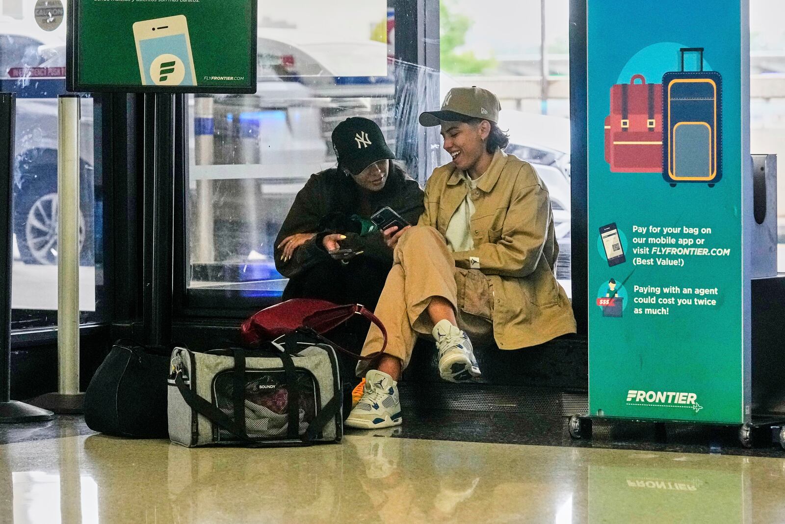 Passengers consult their mobile phones at Newark Liberty International Airport, in New Jersey, Friday, May 23, 2025. (AP Photo/Richard Drew)
