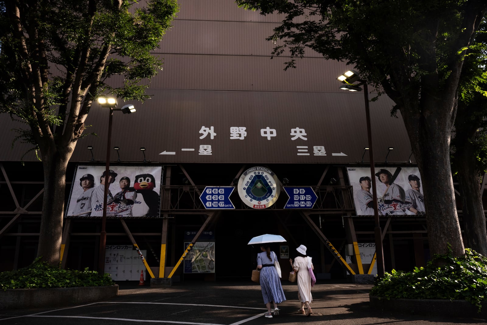 Visitors walk past the Jingu stadium in Tokyo, Monday, June 30, 2025. (AP Photo/Louise Delmotte)