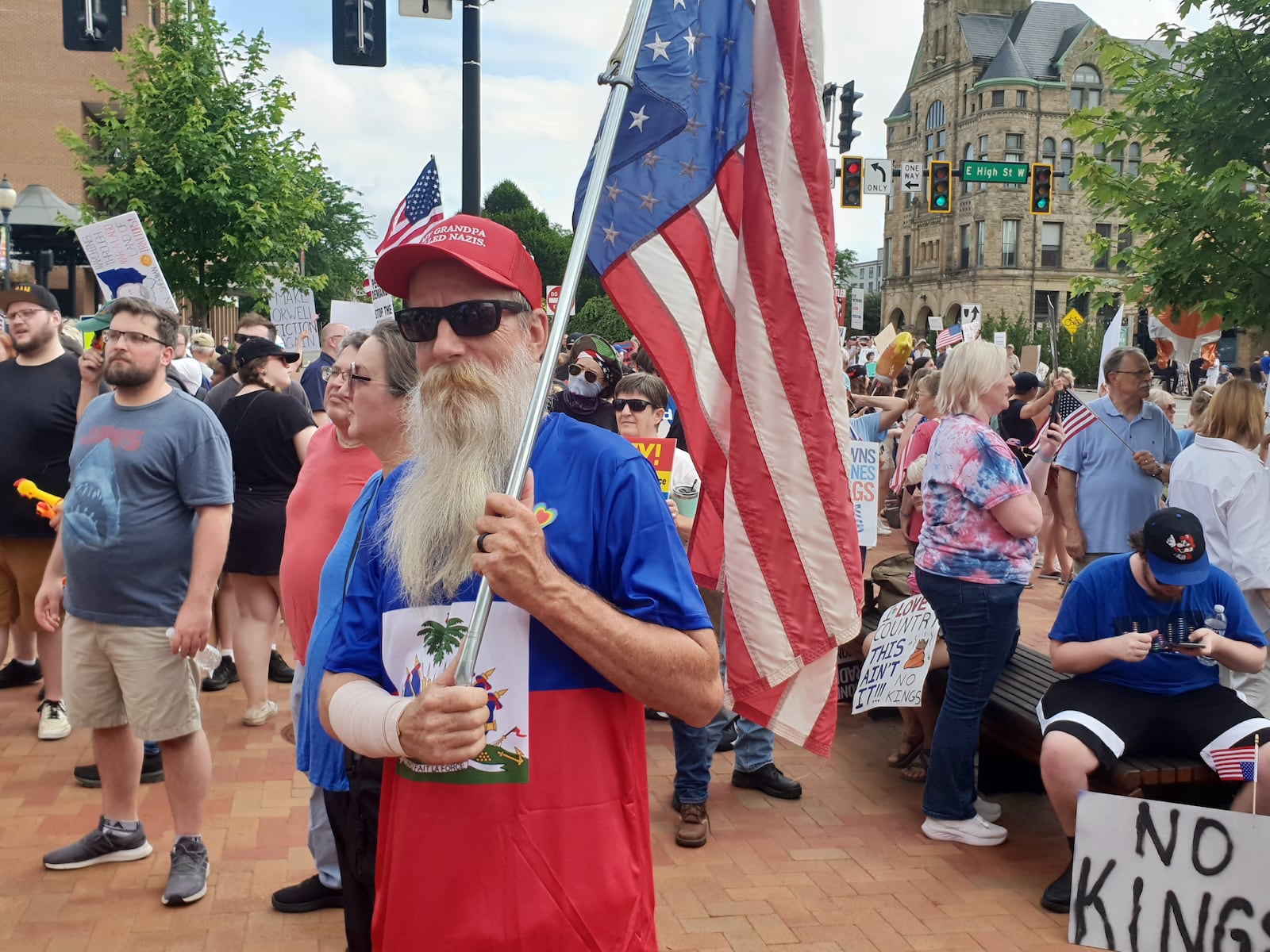 This protester poses in his Haitian shirt while holding an American flag during Springfield's No Kings rally.