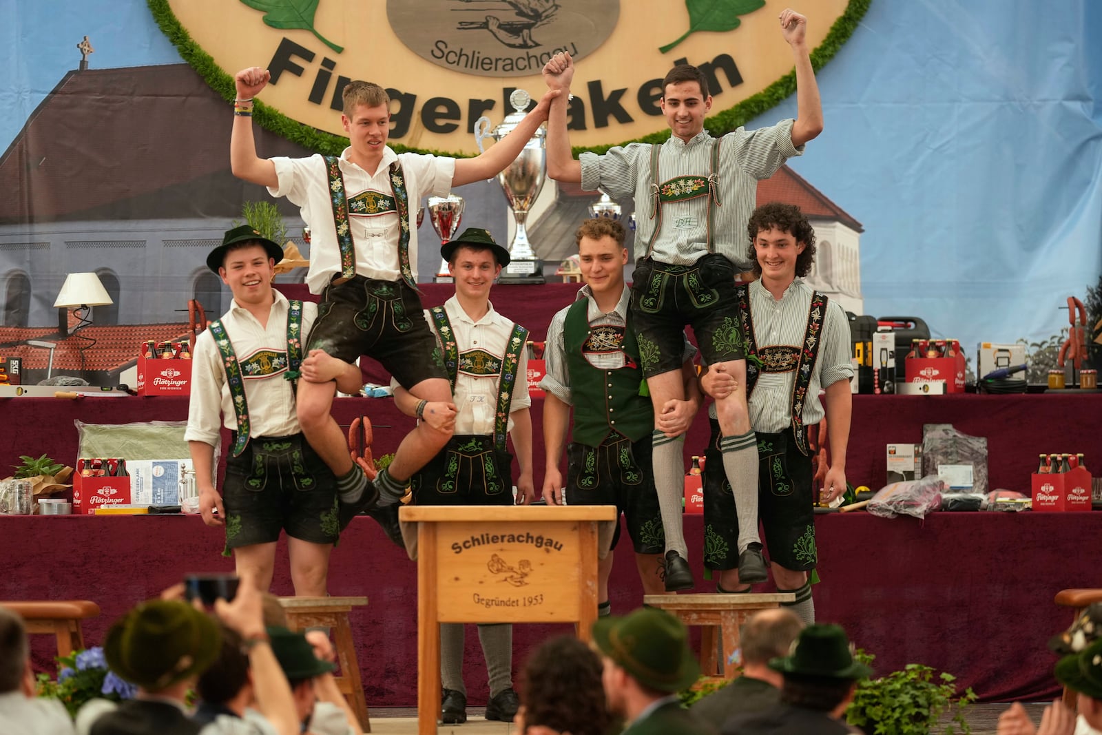 Competitors celebrates after their bouts while they try to pull the opponents over the table at the German Championships in Fingerhakeln or finger wrestling, in Pang, near Rosenheim, Germany, Sunday, April 27, 2025. (AP Photo/Matthias Schrader)