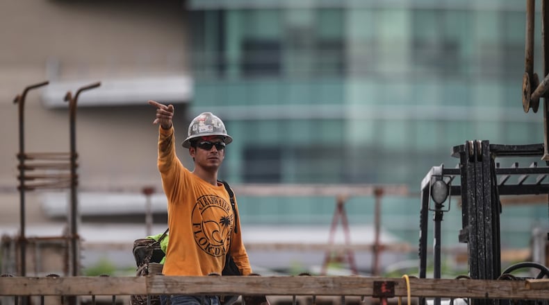 Linhko Contracting carpenter Ronald Coroner guilds a bucket of concrete to the second floor of The Monument Apartments building under construction at 140 East Monument Ave. Monday June 7, 2021. The workers start at 6 a.m. and work till 2:30pm to avoid the heat of the day. JIM NOELKER/STAFF PHOTO