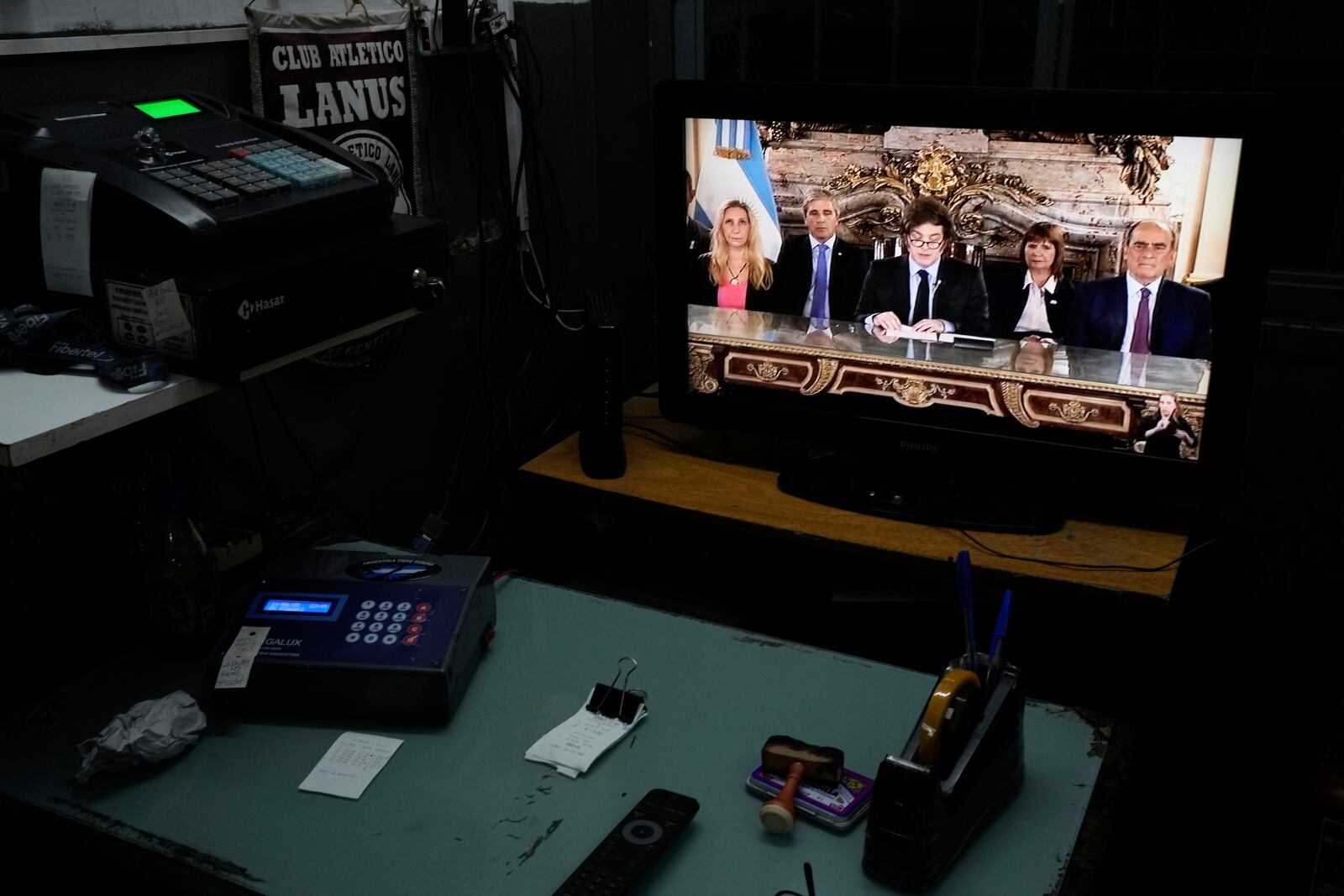 A television screen in a car garage displays a national address by President Javier Milei, accompanied by Cabinet members, in Buenos Aires, Argentina, Friday, April 11, 2025. (AP Photo/Natacha Pisarenko)