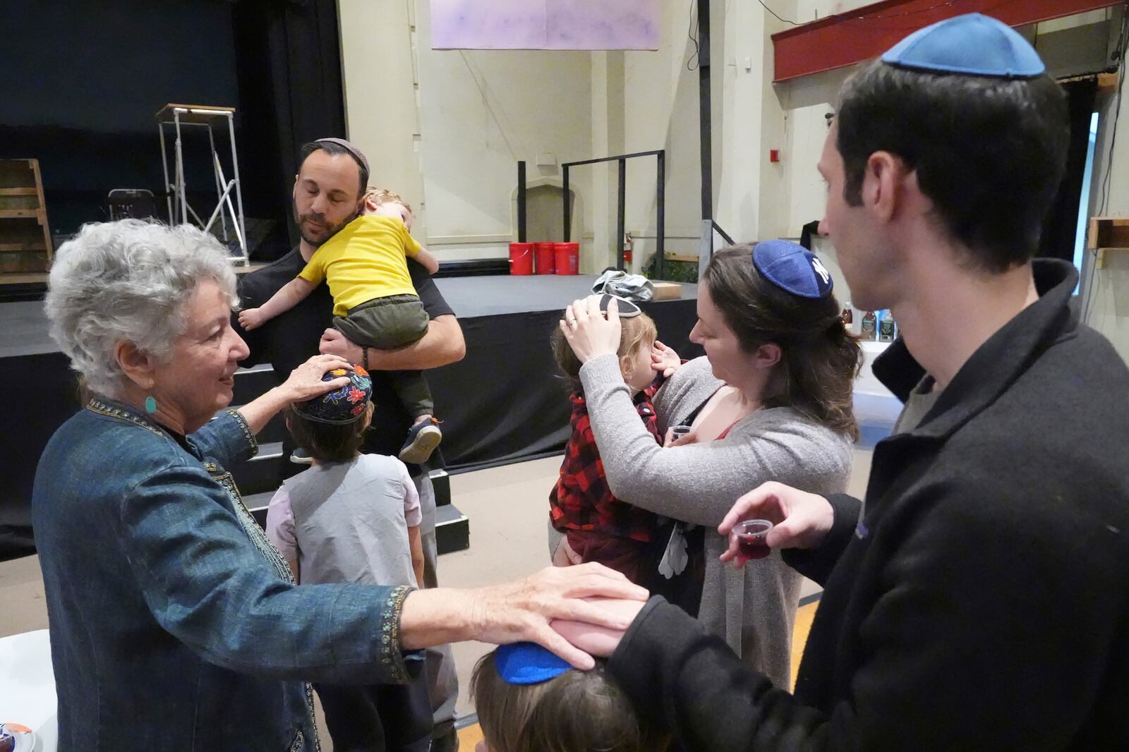 Diane Burr, far left, receives blessing with congregants of the 104-year-old Pasadena Jewish Temple and Center which burned down in the Jan. 2025 Eaton fire, gathered for a Passover Seder at the First United Methodist Church in Pasadena, Calif. on Friday, April 4, 2025. (AP Photo/Damian Dovarganes)
