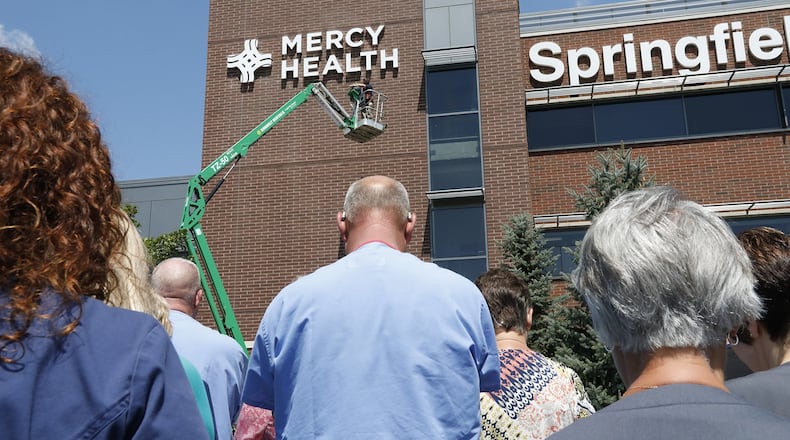 Pictured in August 2017, employees at Springfield Regional Medical Center bow their heads in prayer as a new Mercy Health sign is unveiled. The Collaboratory, the Mercy Health Foundation, the Turner Foundation, the nonprofit Undue Medical Debt and others are currently working on a campaign to eliminate $9.1 million in medical debt in Clark County by raising $51,000 to purchase that debt and forgive it. Ben Merick, vice president of market operations for the Springfield market, said Mercy Health's participation in these efforts stem from the organization's religious roots. BILL LACKEY/STAFF FILE