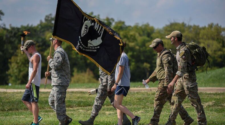 Volunteers from the National Air and Space Intelligence Center carry the POW/MIA flag, scroll and torch during the annual POW/MIA walk/run on Wright-Patterson Air Force Base, Sept. 20, 2018. Runners/walkers carried the POW/MIA flag and torch continuously for 24 hours to honor all past and present POW/MIA. (U.S. Air Force photo/Senior Airman Holly Ardern)