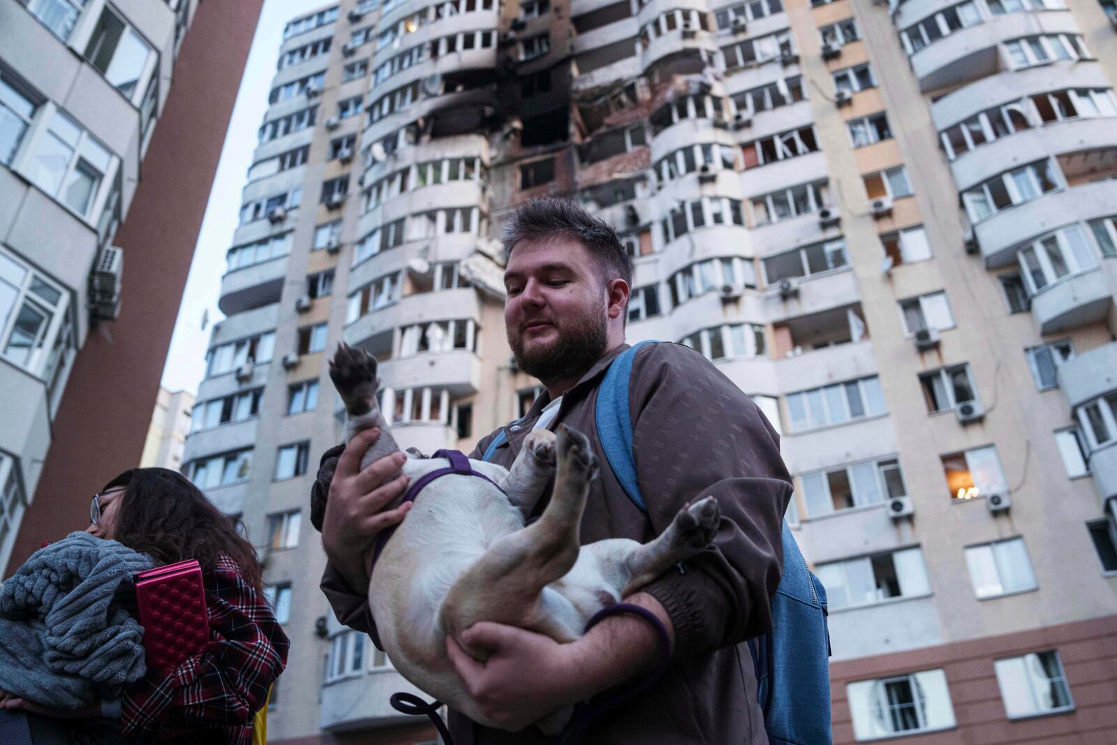 A man carries his dog in front of a residential multi-storey building damaged after a Russian drone strike on Kyiv, Ukraine, on Friday, June 6, 2025. (AP Photo/Evgeniy Maloletka)
