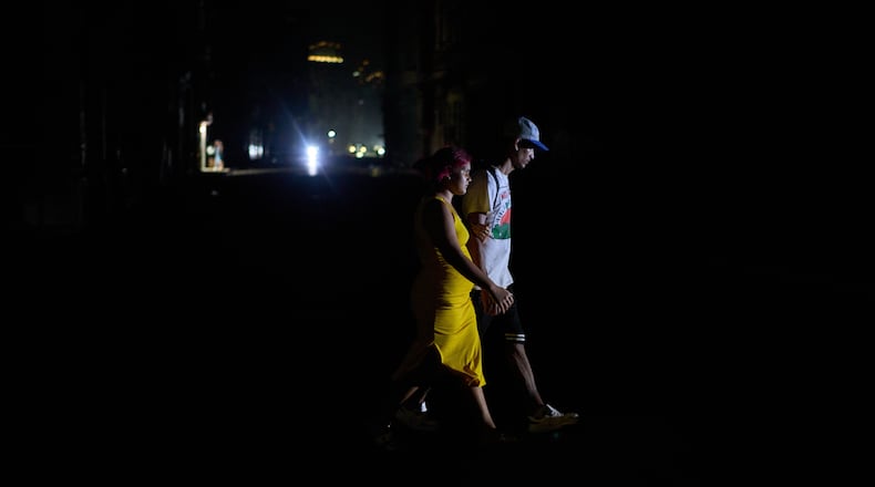 People cross a street during a blackout in Havana, Wednesday, March 4, 2026. (AP Photo/Ramon Espinosa)