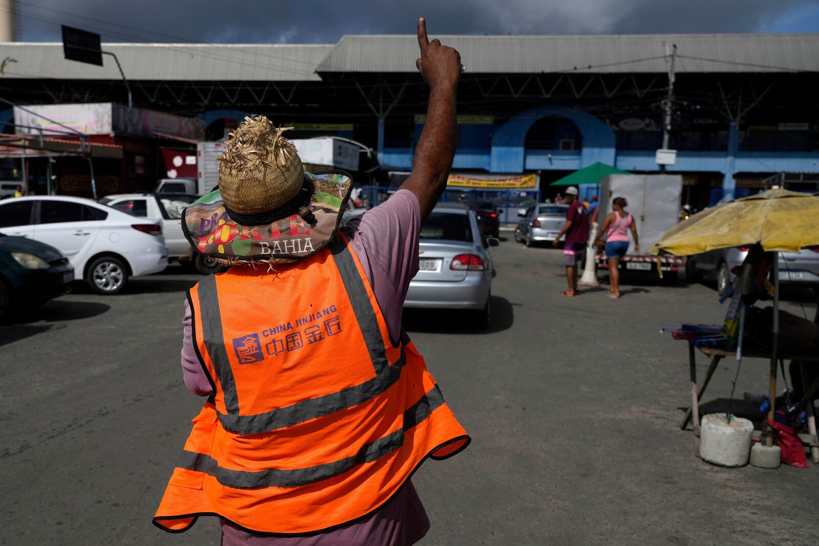 A car attendant wears a vest from the Chinese construction company Jinjiang, in the parking lot of the Municipal Market in Camacari, Bahia state, Brazil, Saturday, March 8, 2025. (AP Photo/Eraldo Peres)